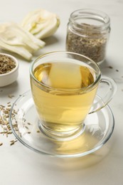 Photo of Aromatic fennel tea, seeds and fresh vegetable on white table, closeup