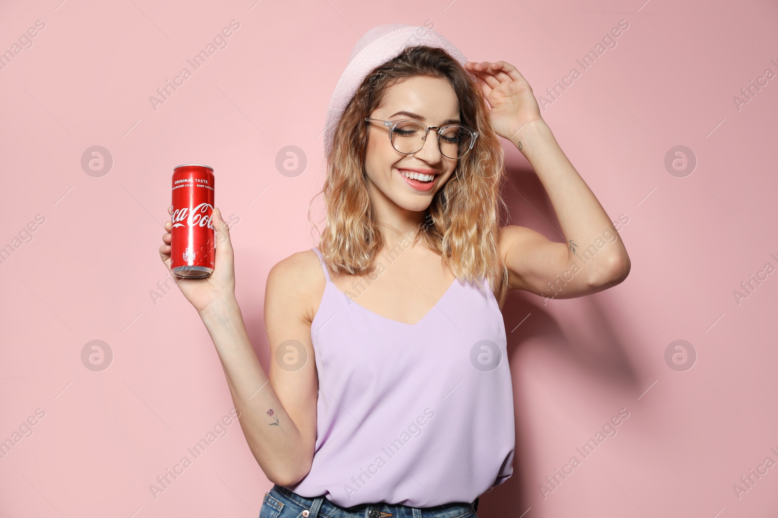 Photo of MYKOLAIV, UKRAINE - NOVEMBER 28, 2018: Young woman with Coca-Cola can on color background