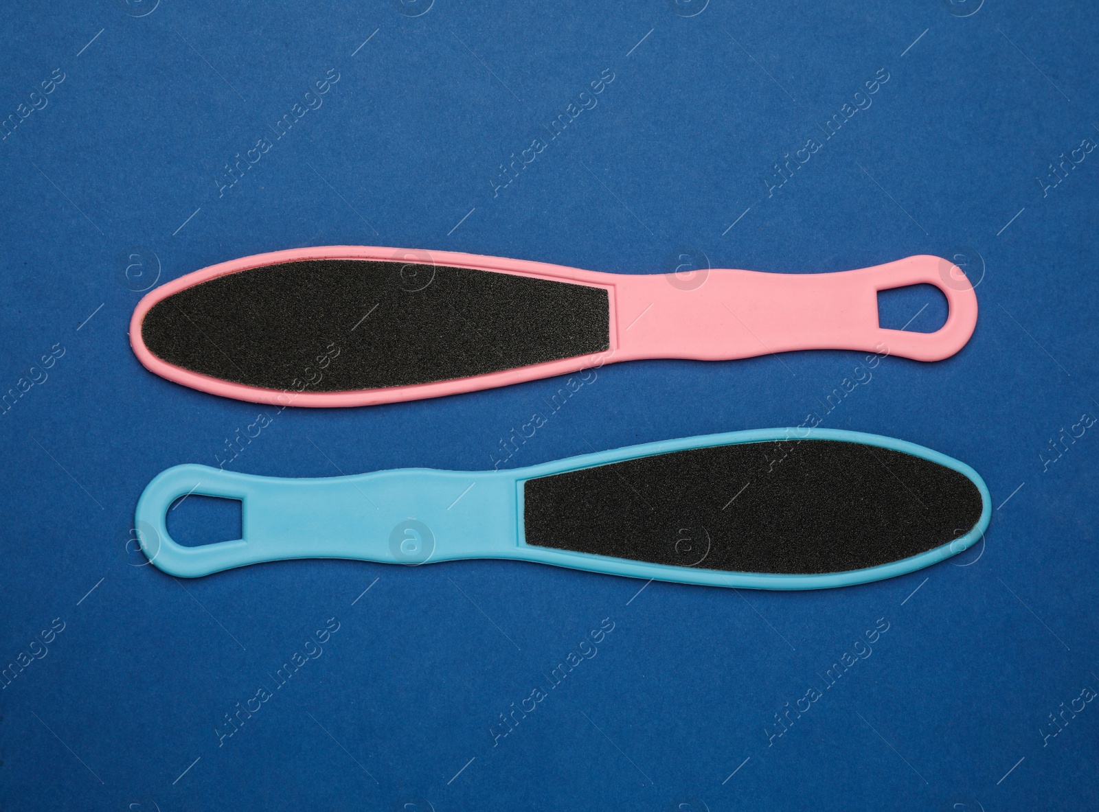 Photo of Colorful foot files on blue background, flat lay. Pedicure tools