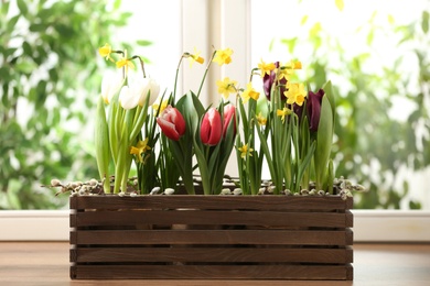 Photo of Beautiful spring flowers in wooden crate on window sill