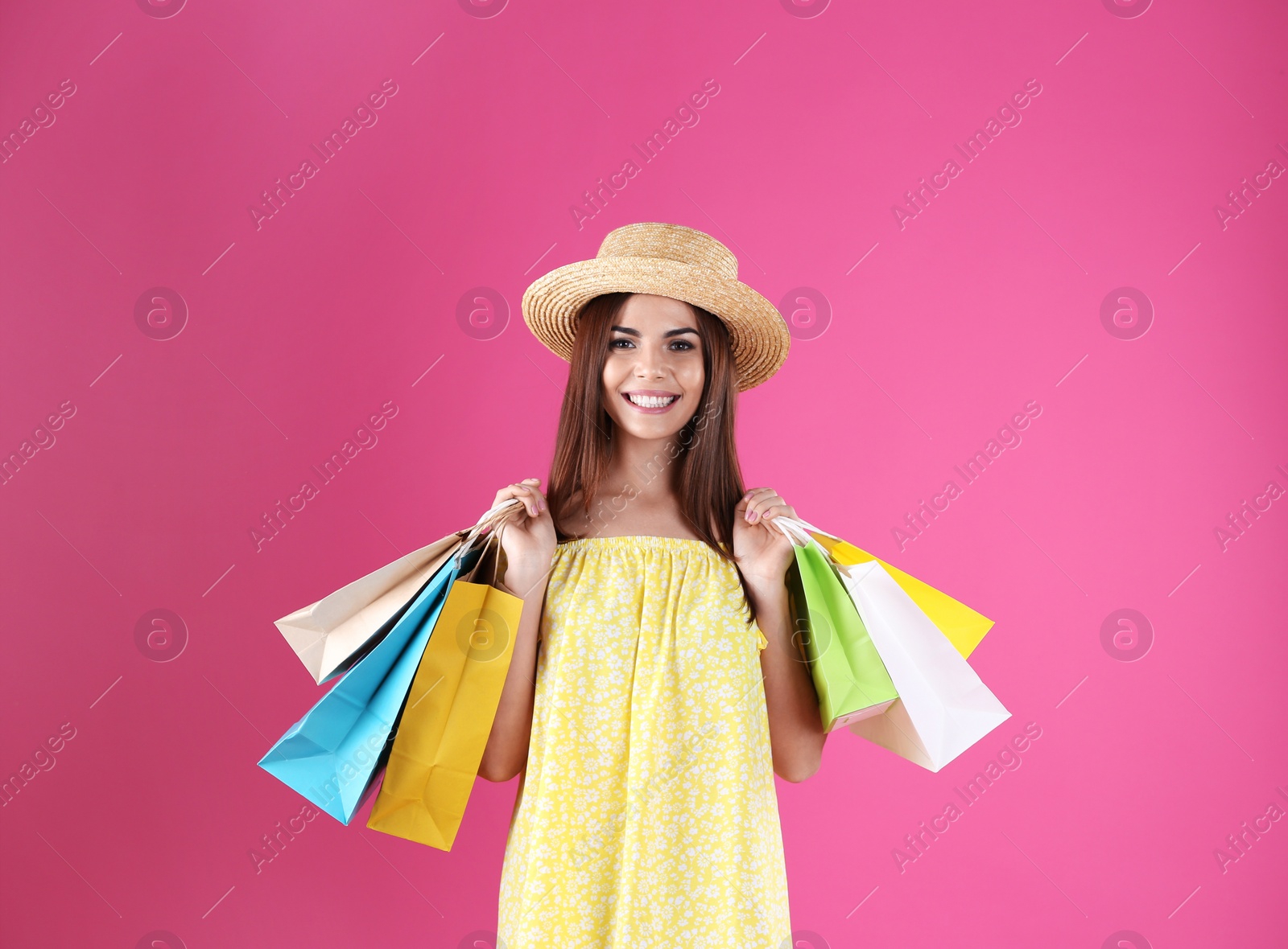 Photo of Young woman with shopping bags on color background