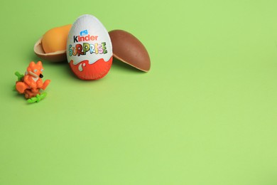 Photo of Sveti Vlas, Bulgaria - July 3, 2023: Kinder Surprise Eggs, plastic capsule and toy on green background, space for text