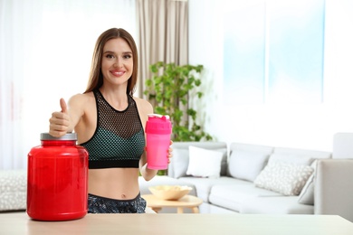 Photo of Young woman with bottle of protein shake at home. Space for text