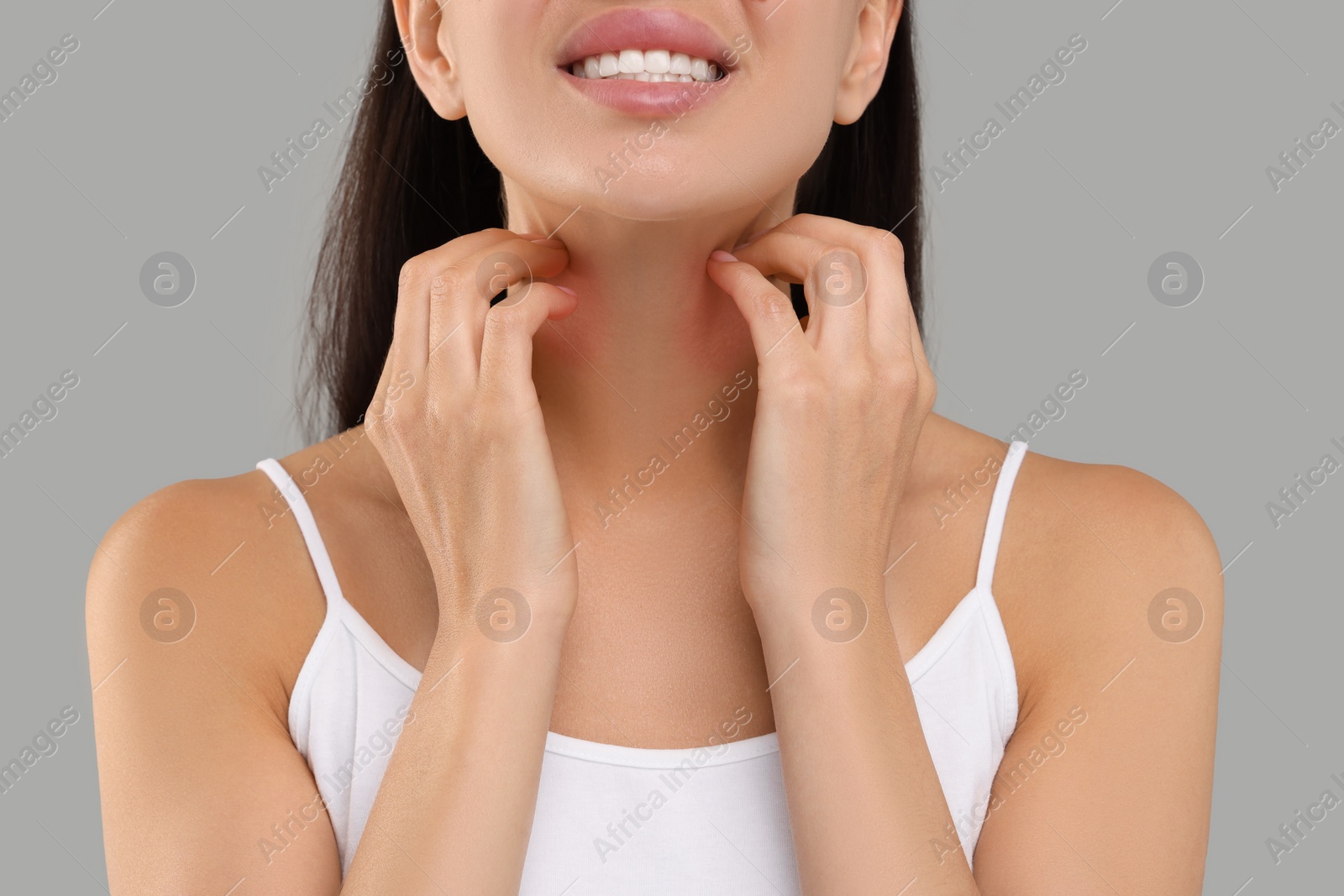 Photo of Suffering from allergy. Young woman scratching her neck on light grey background, closeup