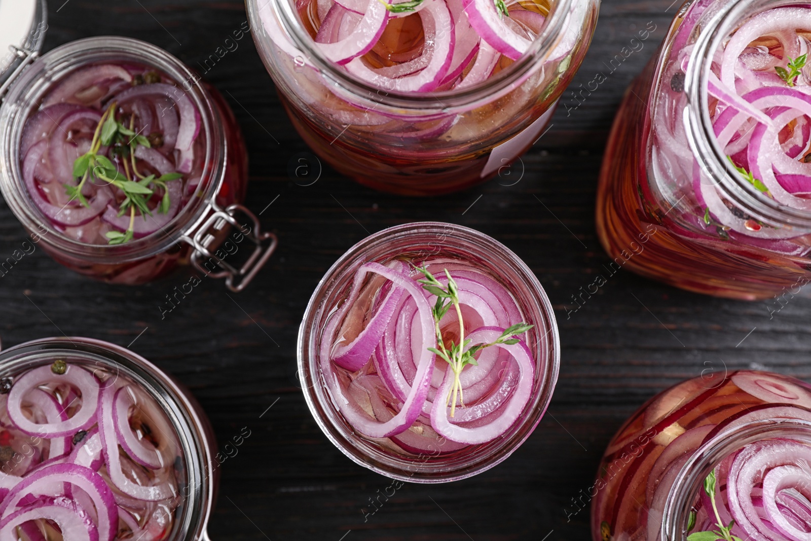 Photo of Flat lay composition with jars of pickled onions on wooden table