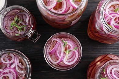 Flat lay composition with jars of pickled onions on wooden table