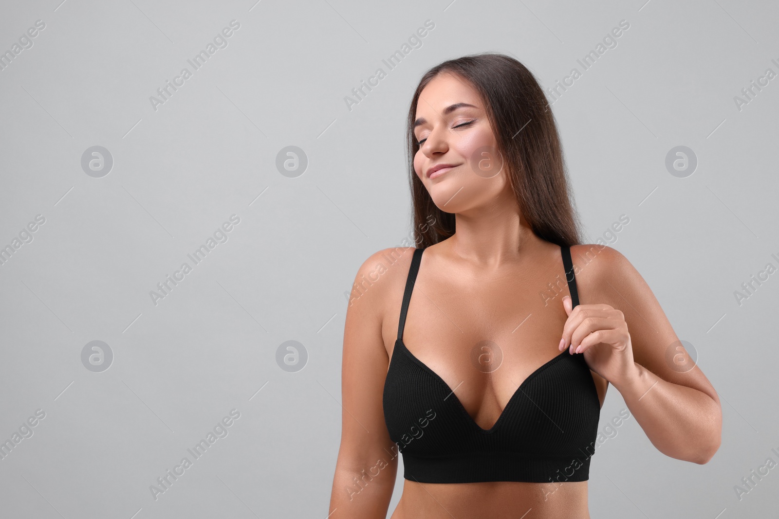 Photo of Portrait of young woman with beautiful breast on light grey background. Space for text