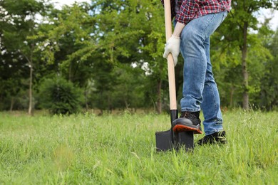 Photo of Worker digging soil with shovel outdoors, closeup