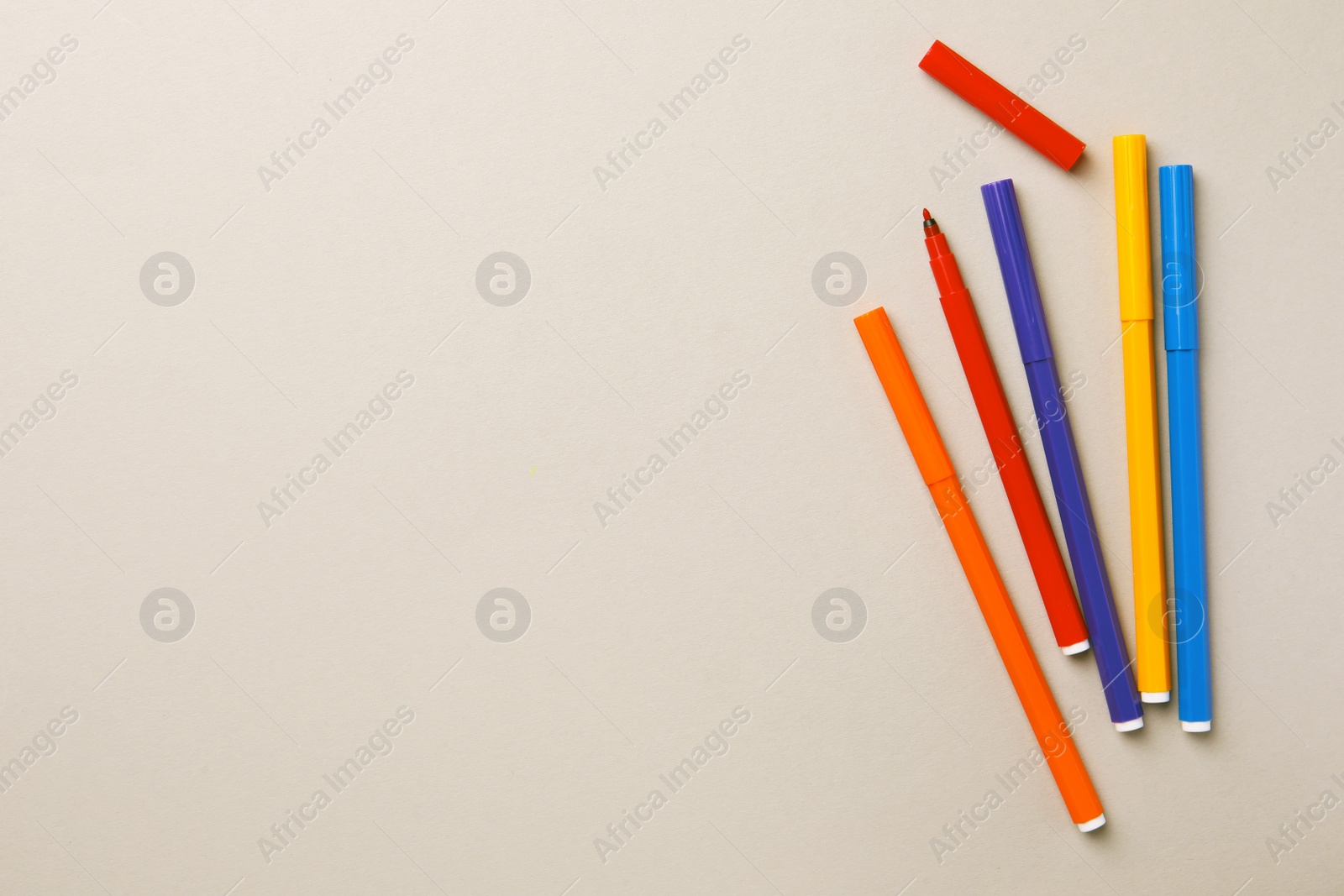 Photo of Many bright markers on light grey background, flat lay. Space for text