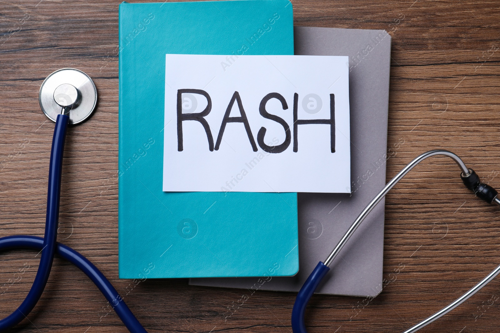 Photo of Sheet of paper with word Rash, notebooks and stethoscope on wooden table, flat lay