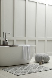 Modern ceramic bathtub near white wall indoors