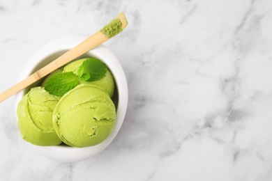 Photo of Tasty matcha ice cream in bowl and spoon with powder on white marble table, top view. Space for text