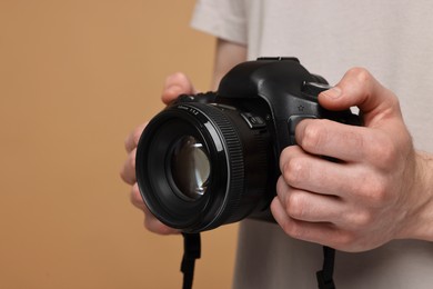 Photo of Photographer holding camera on beige background, closeup