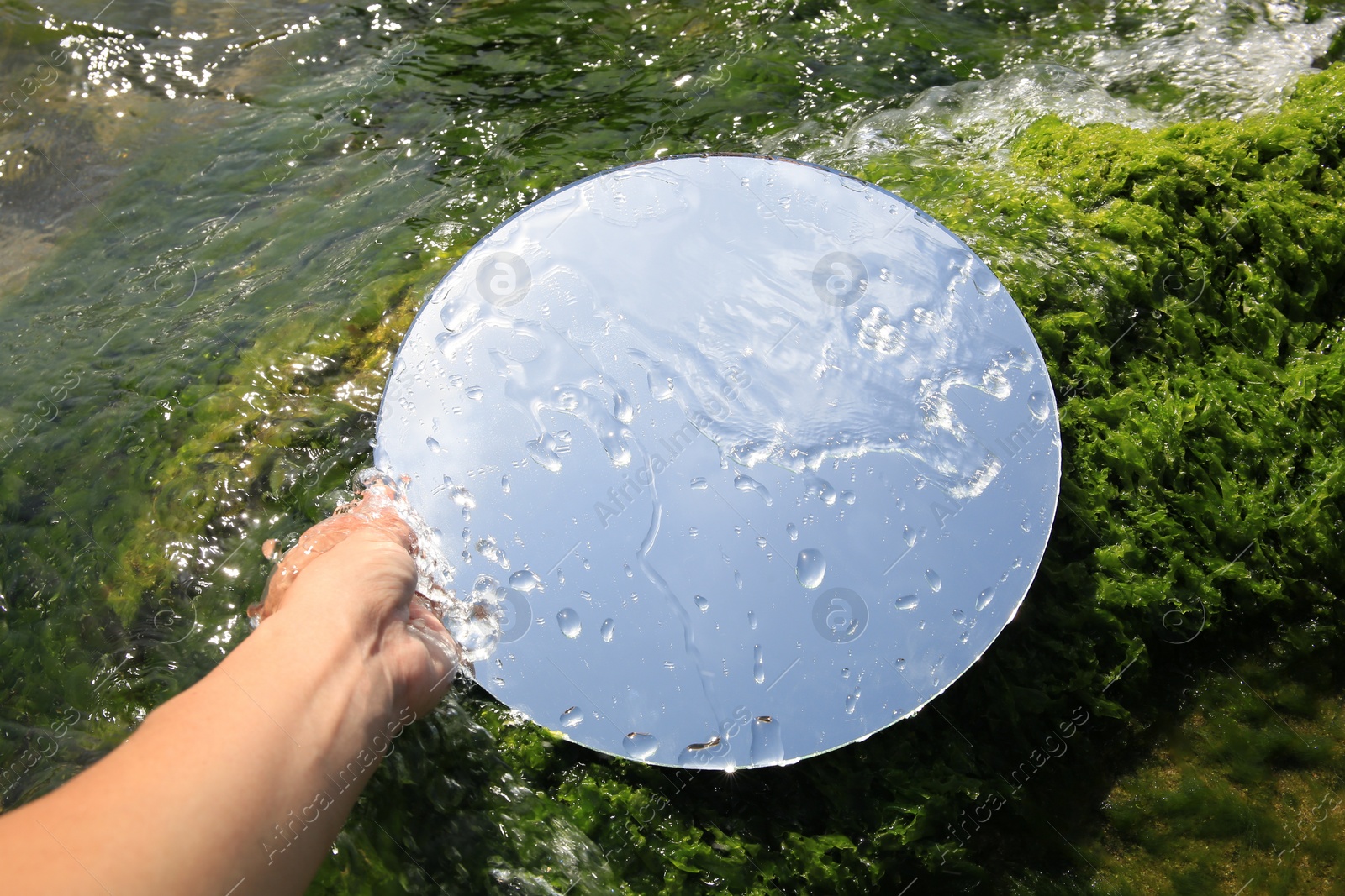 Photo of Woman holding round mirror on seaweed near sea, closeup