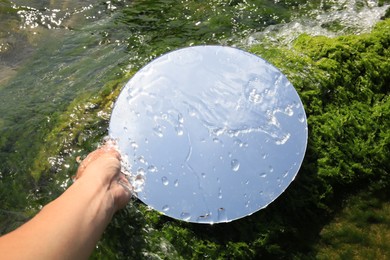 Photo of Woman holding round mirror on seaweed near sea, closeup