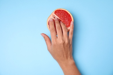 Young woman touching half of grapefruit on blue background, top view. Sex concept