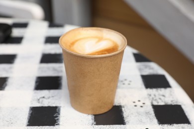 Photo of Takeaway paper cup with hot coffee on table outdoors