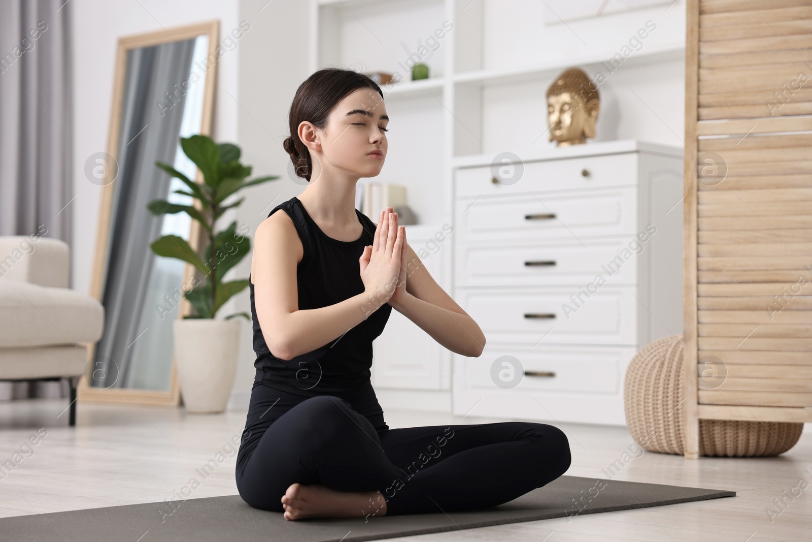 Photo of Beautiful girl meditating on yoga mat at home