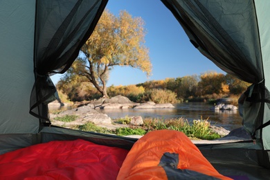 Camping tent with sleeping bags in wilderness, view from inside