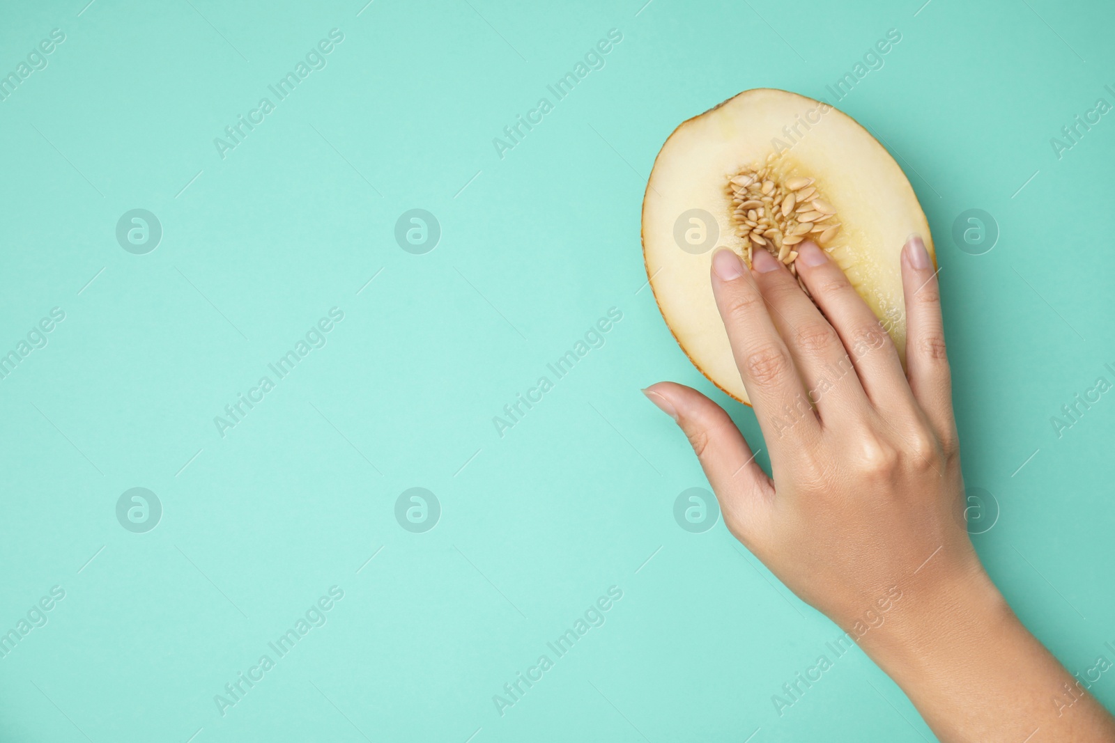 Photo of Young woman touching half of melon on turquoise background, top view with space for text. Sex concept