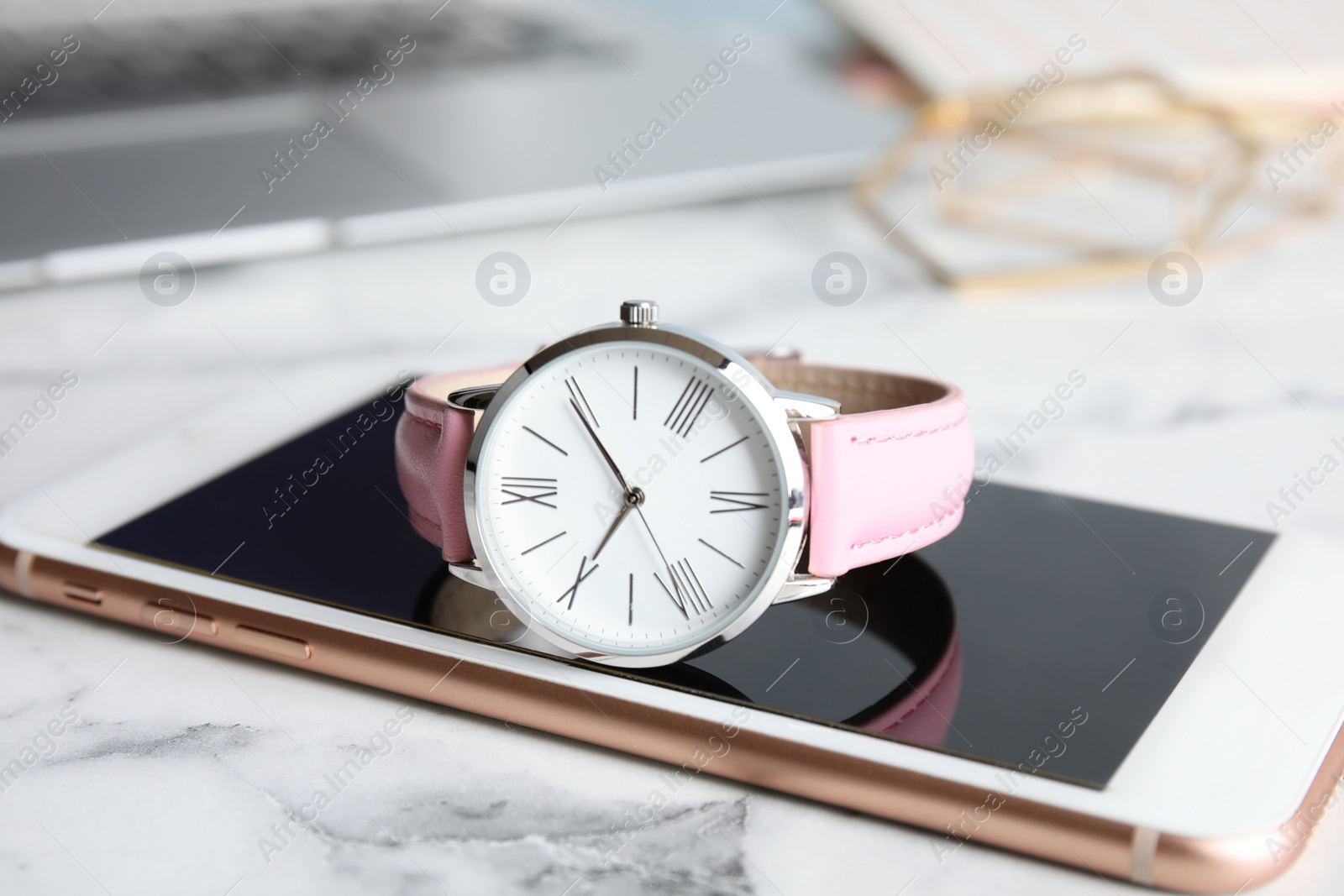 Photo of Stylish wrist watch with modern smartphone on marble table. Fashion accessory