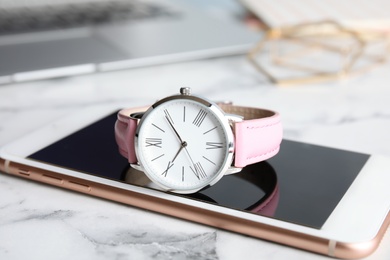 Stylish wrist watch with modern smartphone on marble table. Fashion accessory