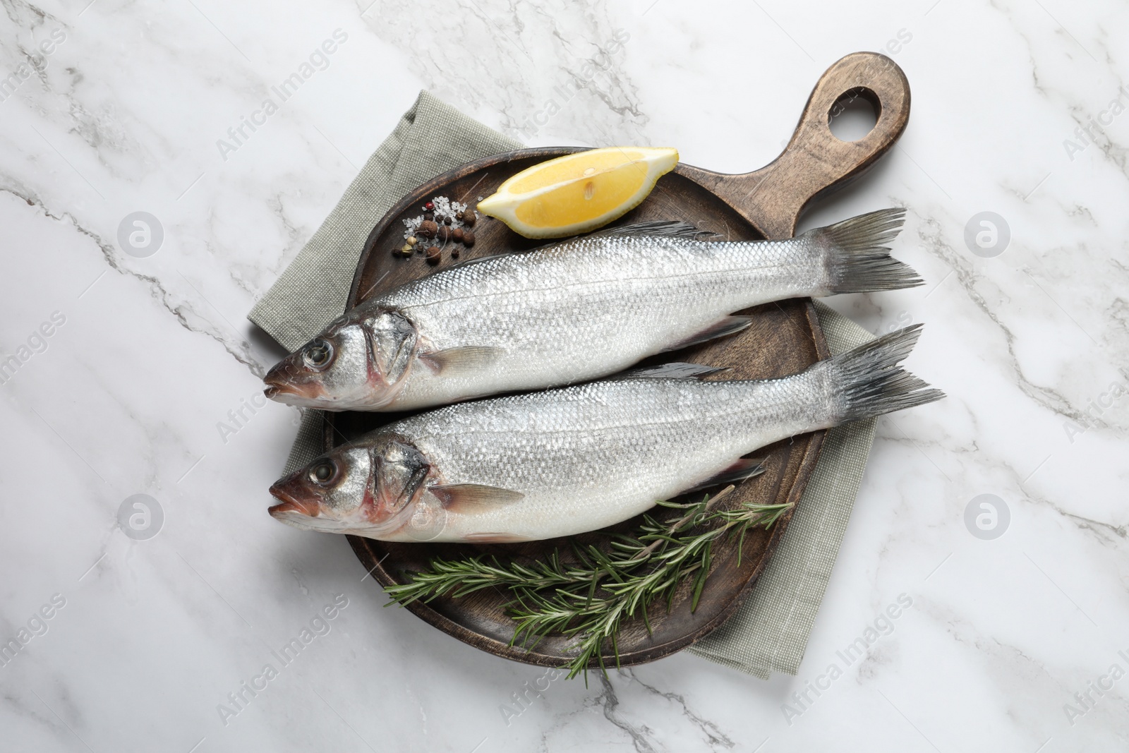 Photo of Tasty sea bass fish and spices on white marble table, top view