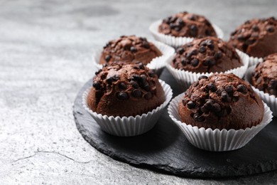 Tasty chocolate muffins on grey textured table, closeup. Space for text