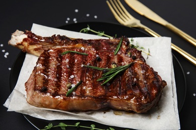 Photo of Plate with grilled meat steak on black background, closeup