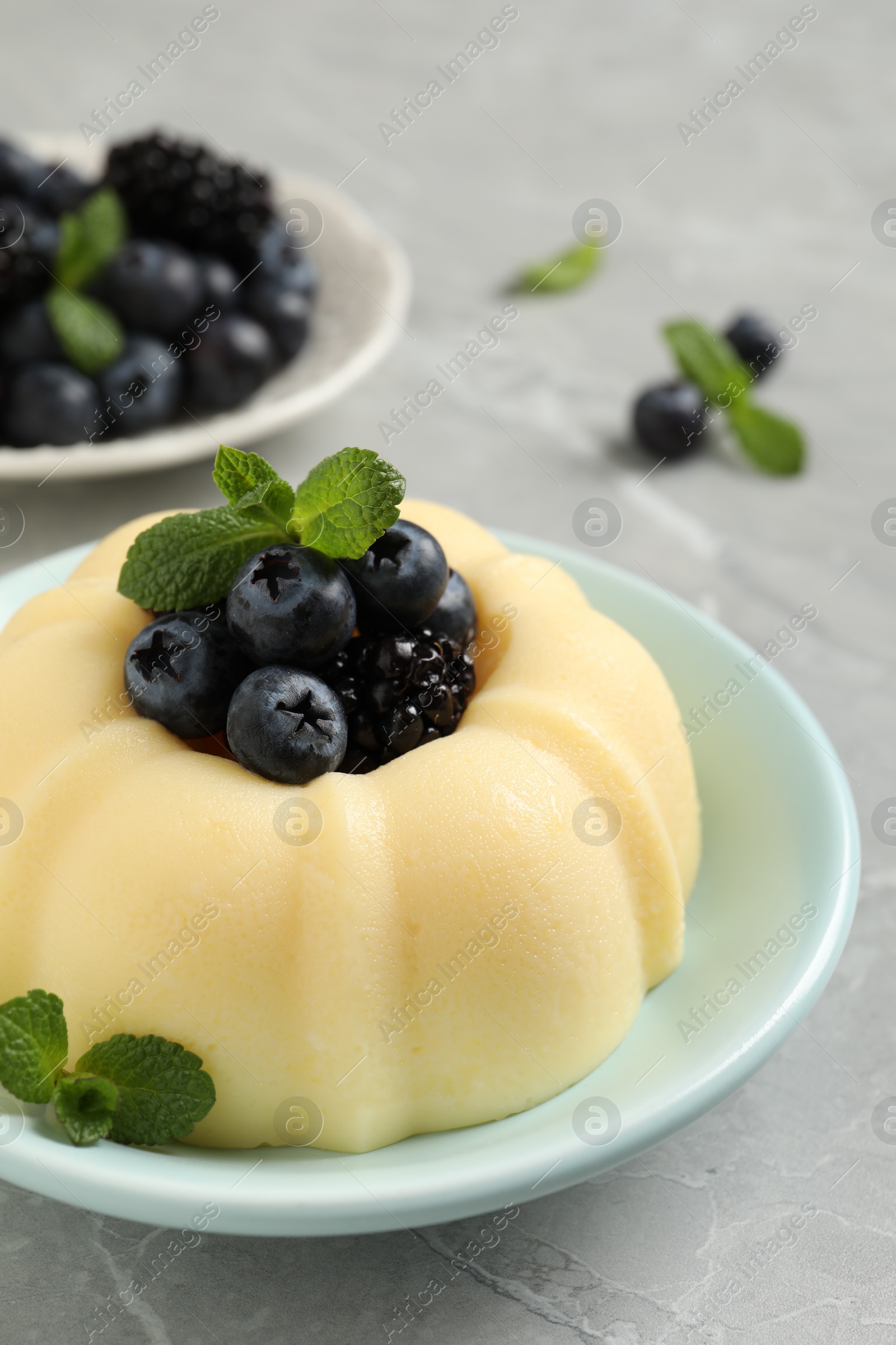 Photo of Delicious semolina pudding with berries on light grey table