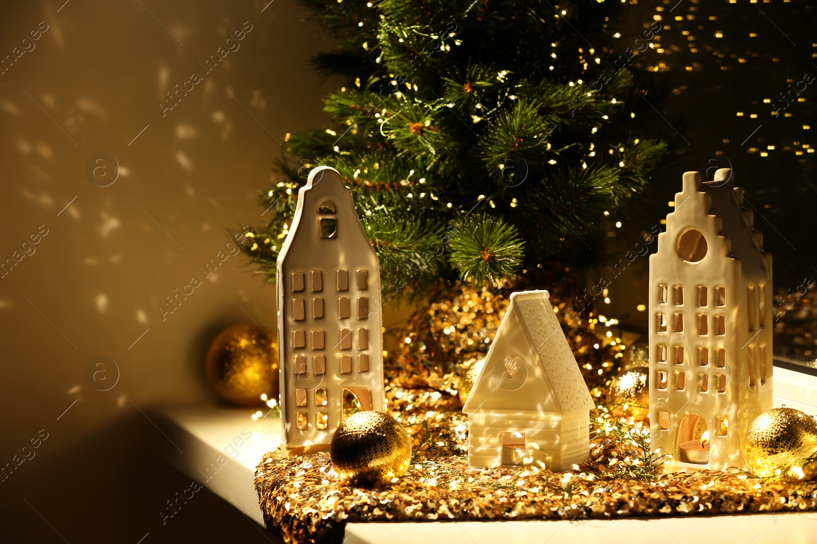 Photo of Beautiful decorative houses, baubles and small Christmas tree on window sill indoors