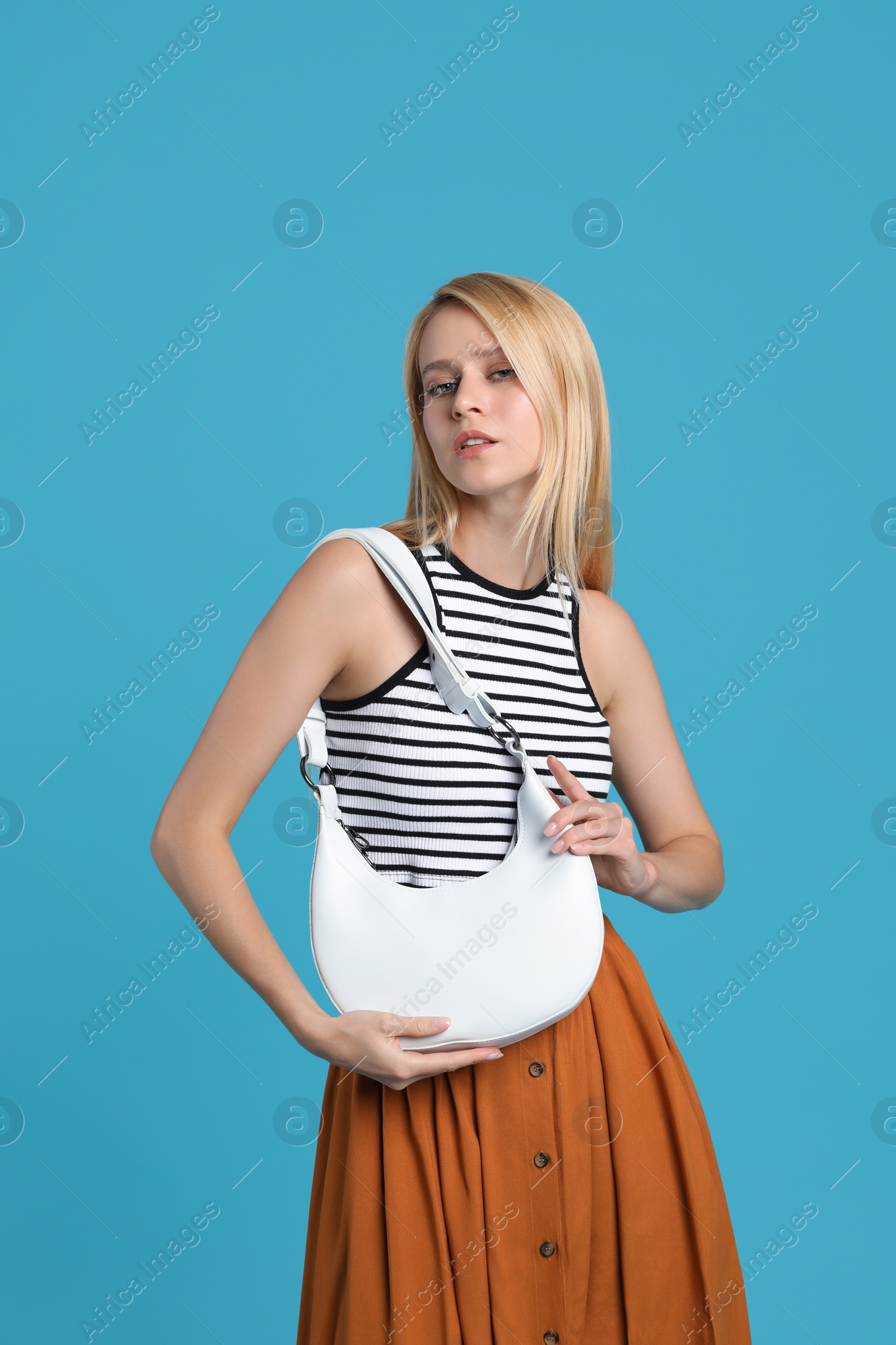 Photo of Beautiful stylish woman with trendy baguette bag on turquoise background