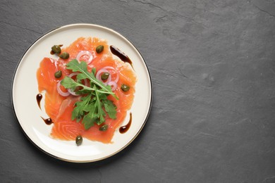 Photo of Delicious salmon carpaccio served on black table, top view. Space for text