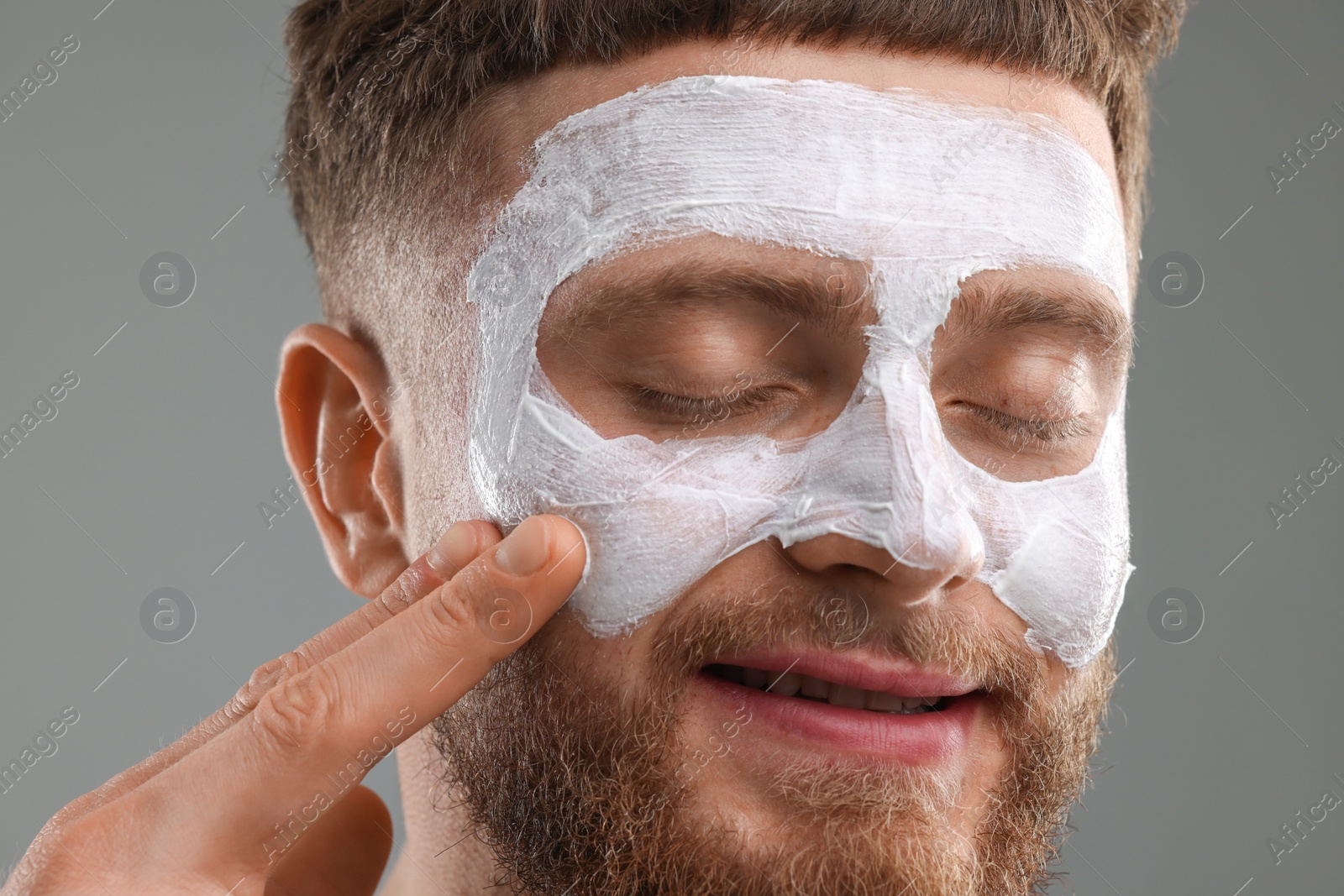 Photo of Handsome man with facial mask on his face against grey background