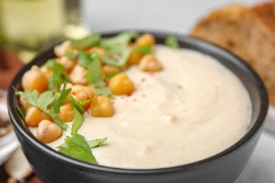 Tasty chickpea soup in bowl, bread and spices served on table, closeup