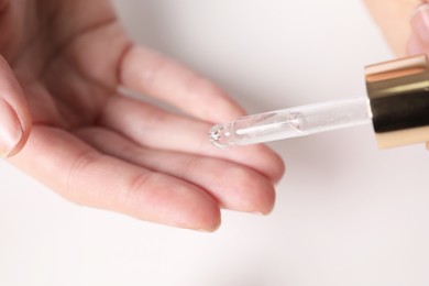 Photo of Dermatologist testing essential oil at white table, closeup