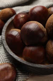 Sweet fresh edible chestnuts on light wooden table, closeup