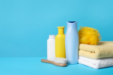 Photo of Baby cosmetic products, accessories and towels on light blue background. Space for text