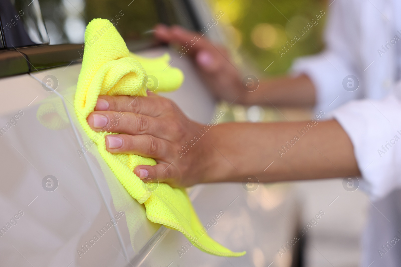 Photo of Woman cleaning car with rag outdoors, closeup view