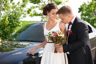 Happy bride and groom near car outdoors