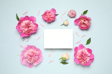 Photo of Beautiful peonies and blank card on light blue background, flat lay. Space for text