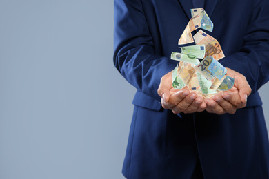 Image of Closeup view of businessman with money on grey background, space for text. Currency exchange