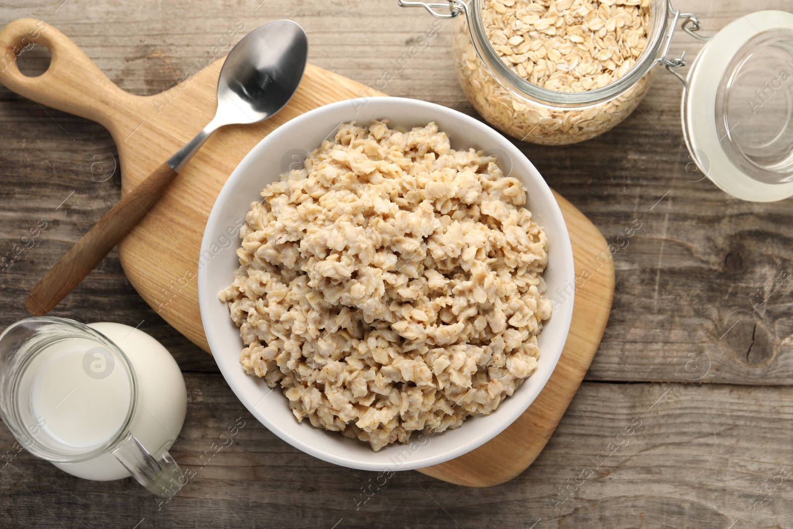 Photo of Tasty boiled oatmeal served on wooden table, flat lay