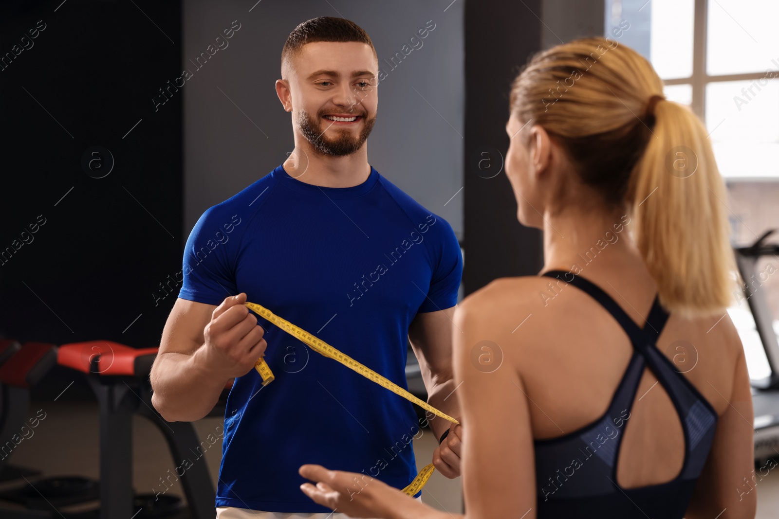 Photo of Trainer having discussion with woman in gym