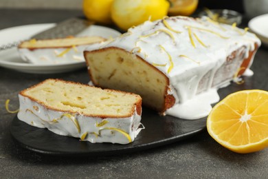 Photo of Tasty lemon cake with glaze and citrus fruit on table, closeup