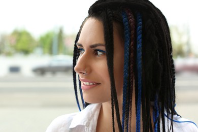 Photo of Beautiful young woman with nose piercing and dreadlocks outdoors