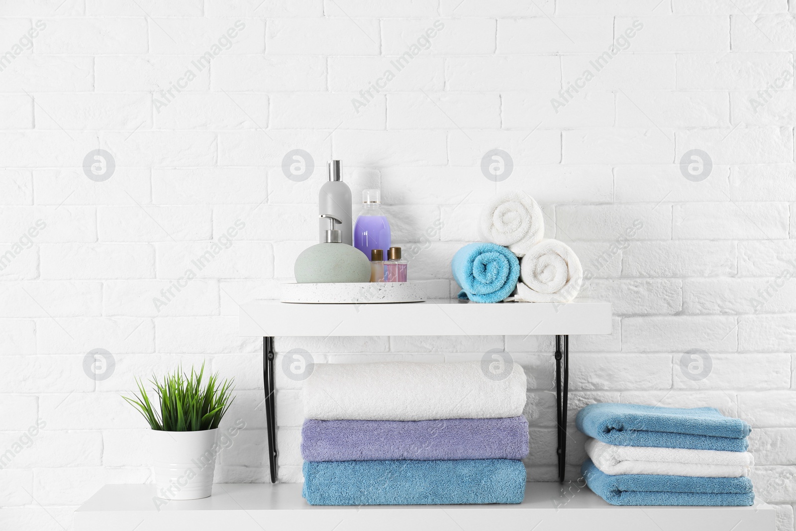 Photo of Shelves with clean towels and toiletries on brick wall