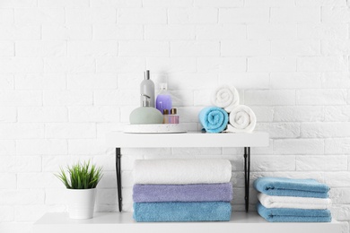 Shelves with clean towels and toiletries on brick wall