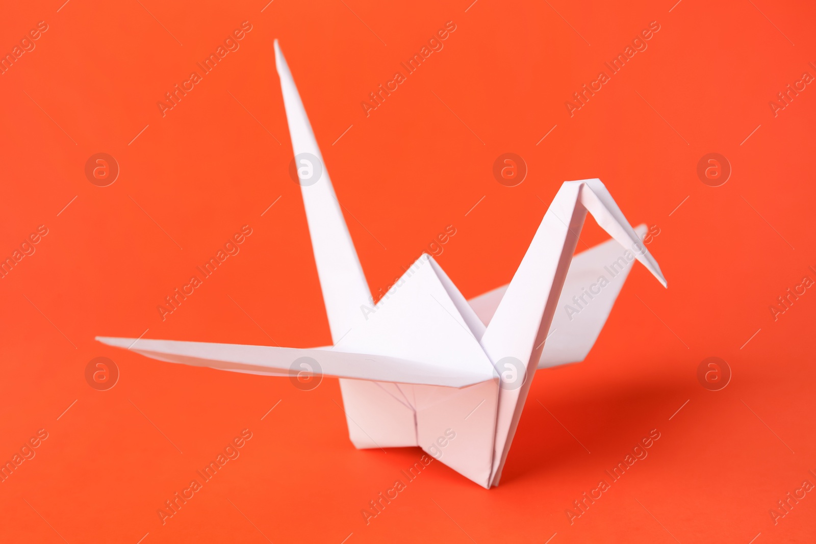 Photo of Origami art. Handmade paper crane on orange background, closeup