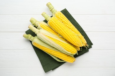 Photo of Tasty fresh corn cobs on white wooden table, top view
